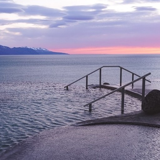 Thermal Baths overlooking lake at GeoSea, Iceland. Sunset and mountains in the background