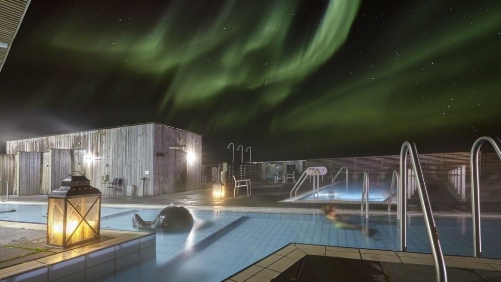 Dark night sky with green Aurora over the top of the Laugarvatn Fontana Geothermal pool